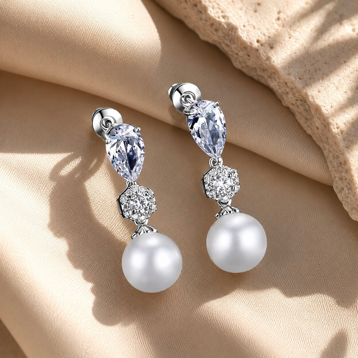 Pearl and crystal drop wedding earrings on a beige fabric background