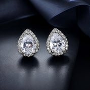 Teardrop-shaped earrings with clear gemstones on a dark fabric background