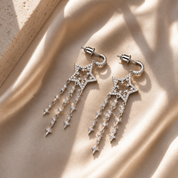Silver star-shaped earrings on a beige fabric background