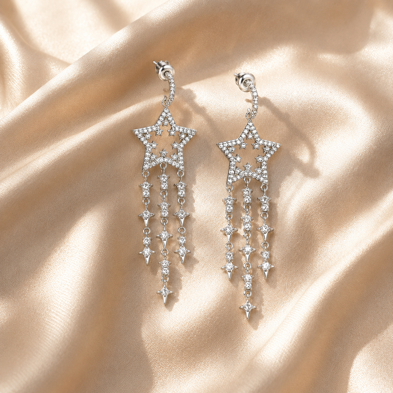 Star-shaped earrings with dangling crystals on a beige fabric background