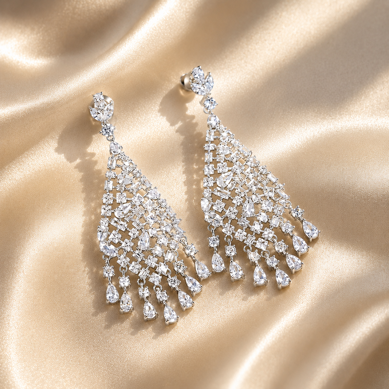 Pair of silver statement chandelier earrings on a beige fabric background