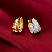 Gold earrings with intricate designs on a red fabric background