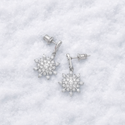 Snowflake-shaped earrings on a white textured background