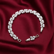 Silver vine leaf bracelet with diamond-like stones on a red fabric background