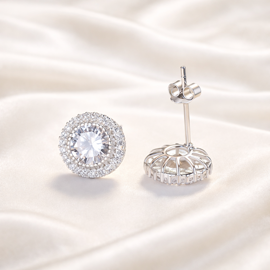 Pair of silver halo earrings with clear gemstones on a satin background