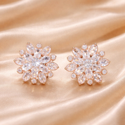 Pair of rose gold and clear crystal flower-shaped earrings on a satin background