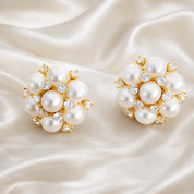 Close-up of gold-plated cluster earrings with white pearls and crystal stones