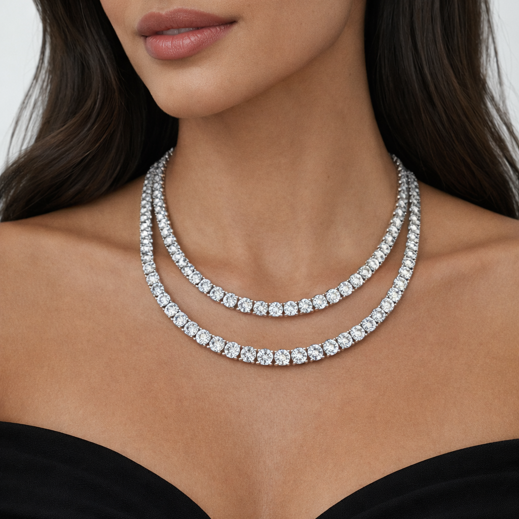 Close-up of a woman wearing two tennis necklaces against a neutral background