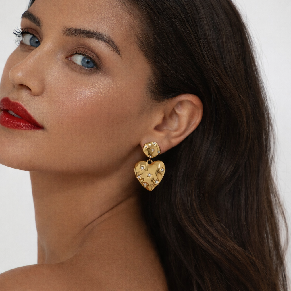 Close-up of a woman wearing gold heart-shaped earrings with a plain background