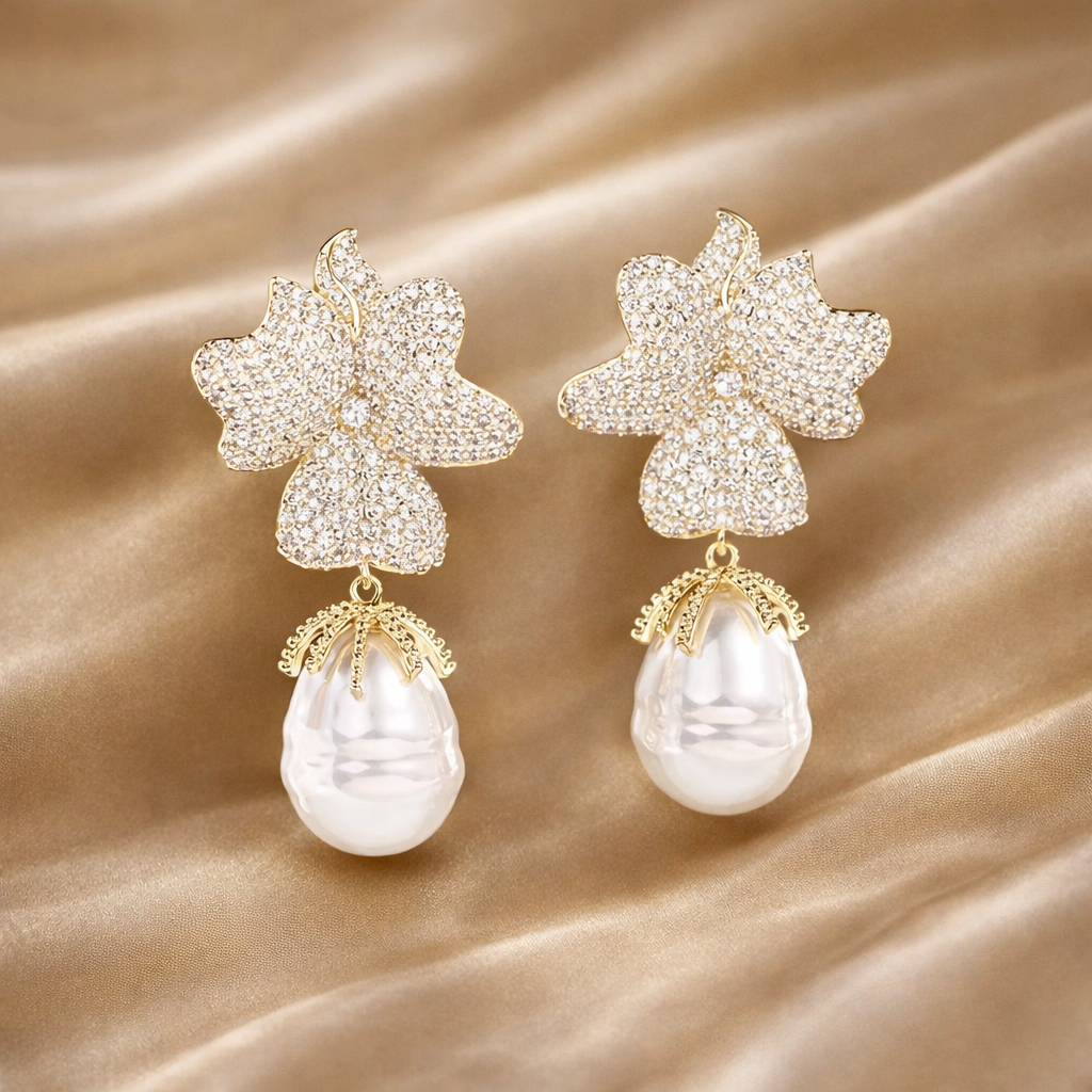 Pair of floral earrings with pearl drops on a beige fabric background