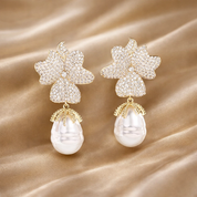 Pair of floral earrings with pearl drops on a beige fabric background