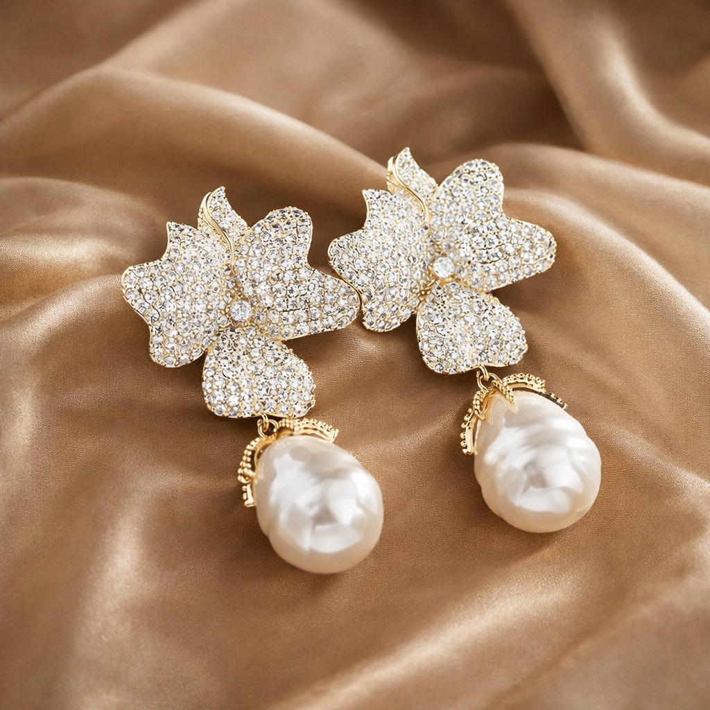 Ornate earrings with floral designs and pearl drops on a beige fabric background
