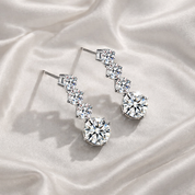 Silver crystal wedding earrings with clear gemstones on a white fabric background